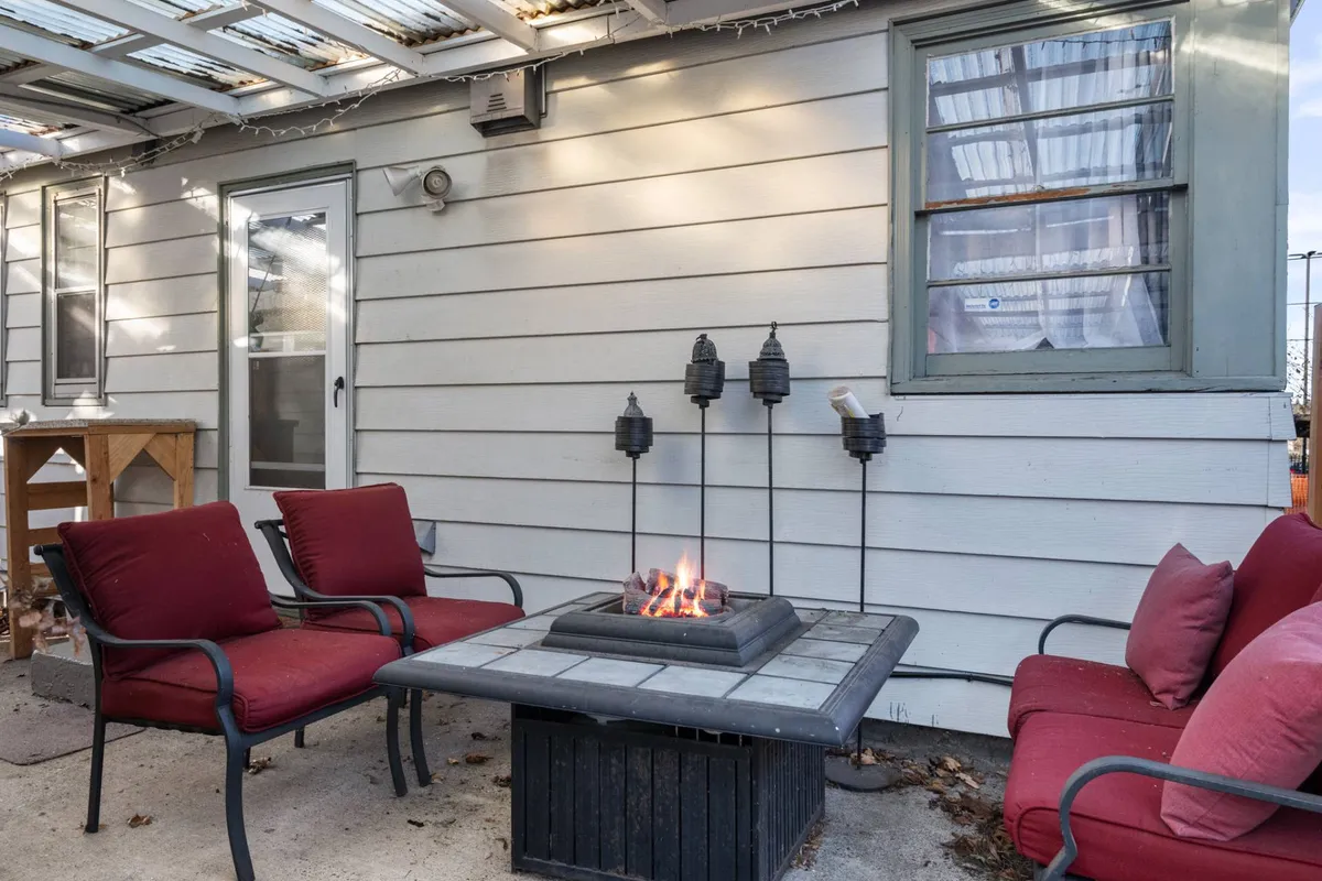 The image shows the exterior patio area of the Kasari condo, featuring a cozy fire pit surrounded by vibrant red chairs and charming outdoor décor, inviting guests to gather and relax in an intimate setting.
