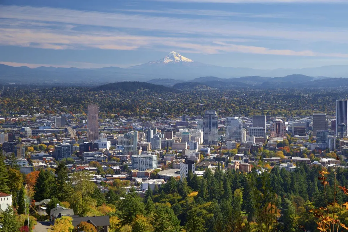 A panoramic view of Portland’s downtown skyline with the impressive Mount Hood in the distance, framed by lush green trees and urban architecture. The image conveys the broader cityscape and the array of activities and sights accessible from the property.