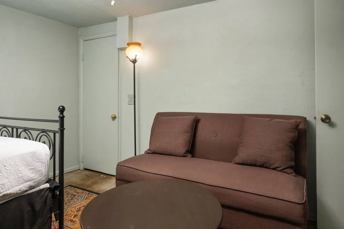 A cozy, intimate corner with a sofa, lamp, and bed, designed for reading, relaxing, and spending quality time with friends. The layout encourages both quiet moments and shared experiences like movie nights.