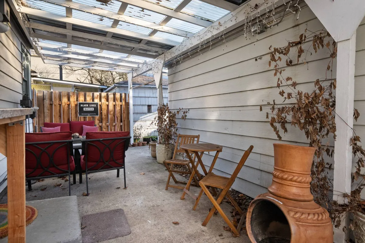 A cozy, calm seating area with red cushions, a wooden table, and a terracotta planter. The space is filled with natural light and evokes the feeling of a welcoming common area where one might relax, read, or enjoy a coffee before heading out. Subtle hints of the outdoors are present, with the planter connecting the interior to the outside world.