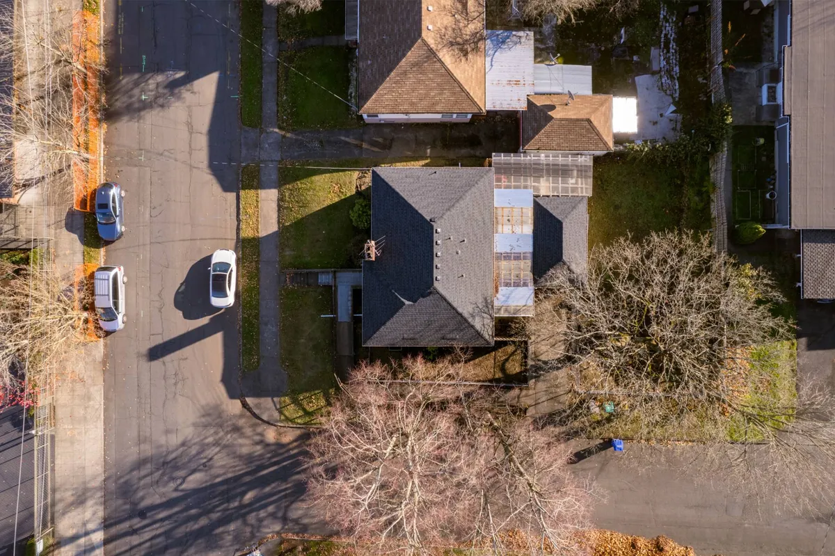 This exterior image showcases the main house surrounded by mature trees and neighboring homes, capturing the peaceful atmosphere of the neighborhood. The scene hints at walkable streets and an inviting environment just outside the doorstep.